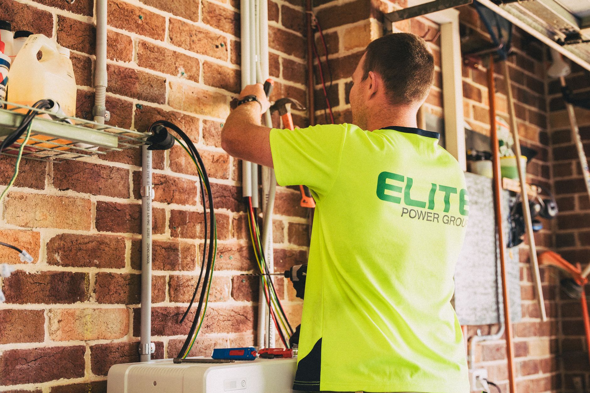 a licensed electrician wiring a bidirectional EV charger on a garage wall